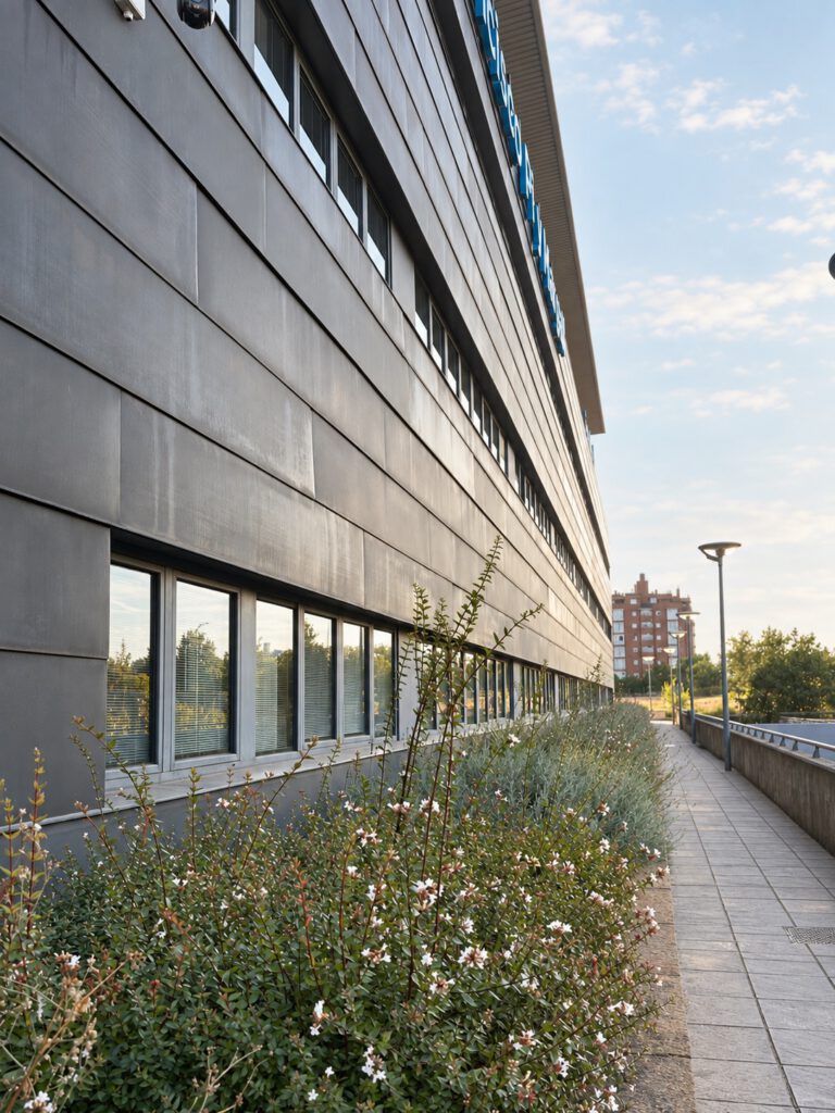 Jardín lineal junto a fachada contemporánea en entorno sanitario.