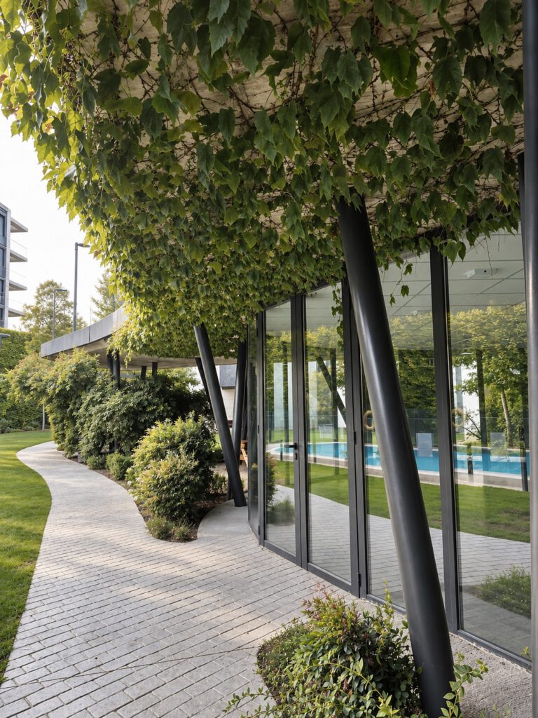 Galería vegetal junto a fachada acristalada en zona común residencial.